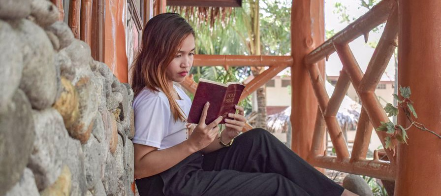 Biblia abierta sobre una mesa junto a un cuaderno y un resaltador, lista para el estudio y la memorización